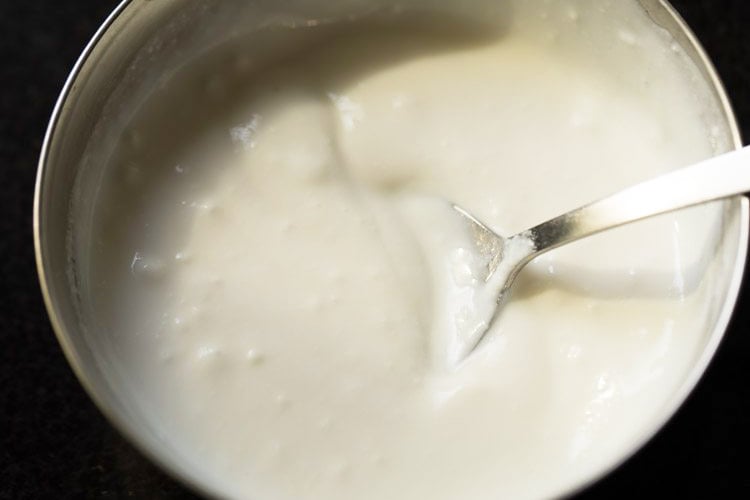 curd (yogurt) being beaten with a spoon.