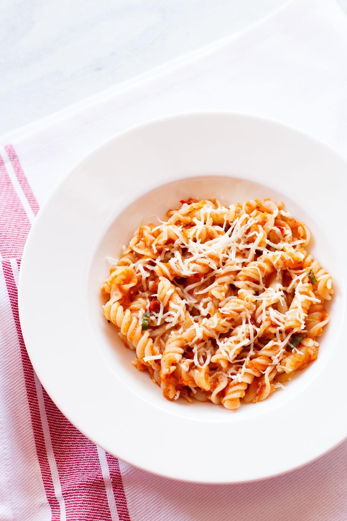 pasta arrabiata in a deep dish on a red bordered white napkin