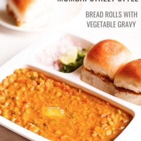 pav bhaji served in a rectangular serving tray with buttered pav and chopped onions, coriander leaves and lemon wedges on a white table with text layovers