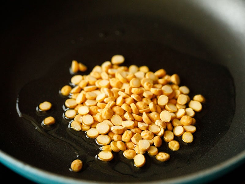 chana dal added to oil in a small cast iron skillet