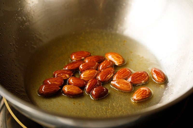 frying almonds in hot ghee for pinni recipe. 