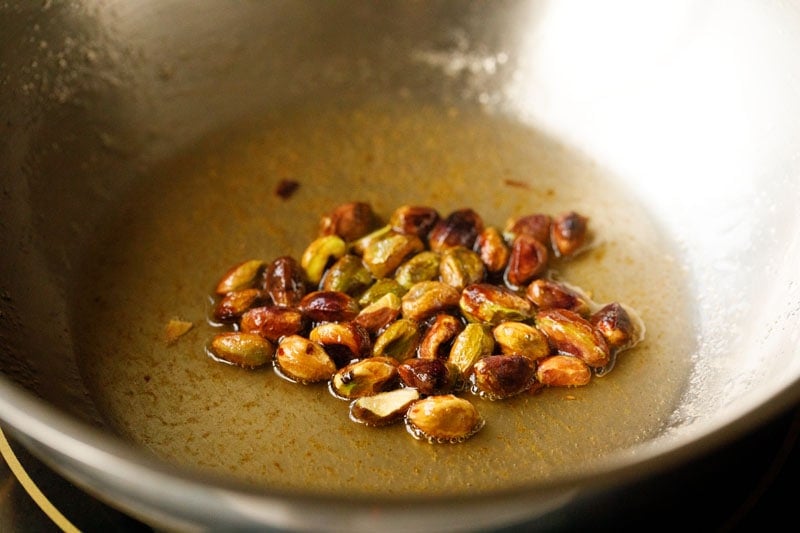 frying pistachios in hot ghee for pinni recipe.