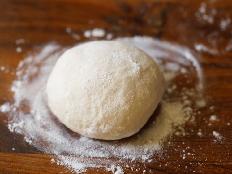 a dough ball dusted with flour on a wooden board