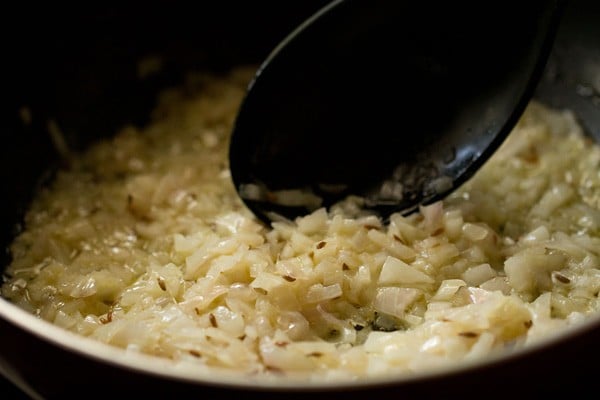 onion being stirred and sautéed with a black spoon