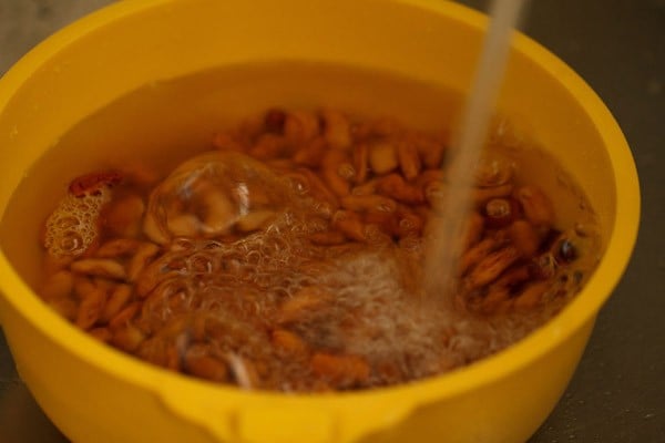 kidney beans being rinsed in water in a yellow bowl