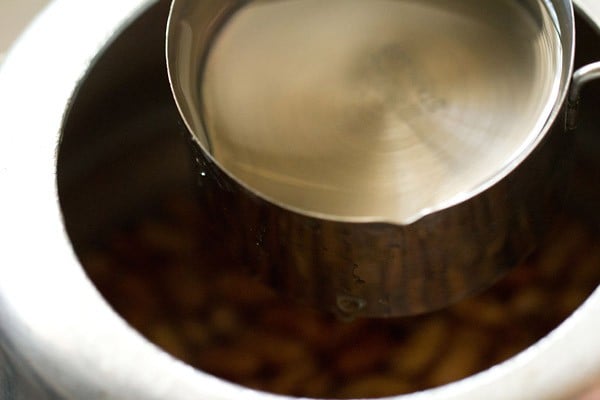 water being added to rajma in a pressure cooker