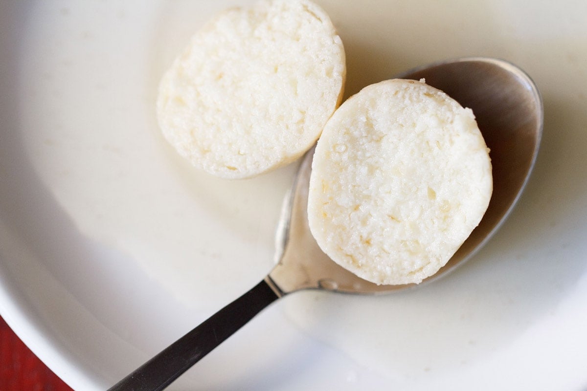 spongy rasgulla cut in half with a spoon to show soft interior