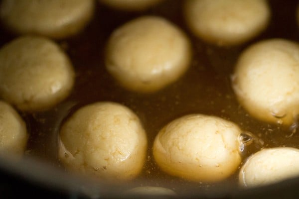 rasgulla balls floating in sugar syrup that isn't bubbling anymore