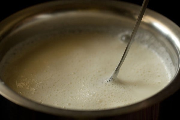 spoon stirring milk to make chenna