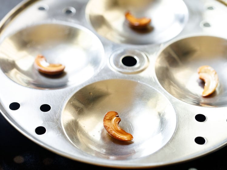 greased idli pan moulds with cashews. 