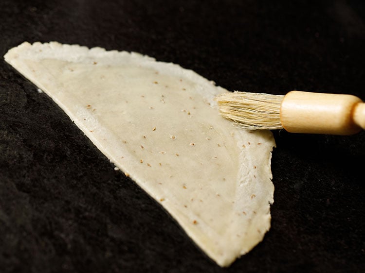 brushing with water with a pastry brush on the sides of the cut dough
