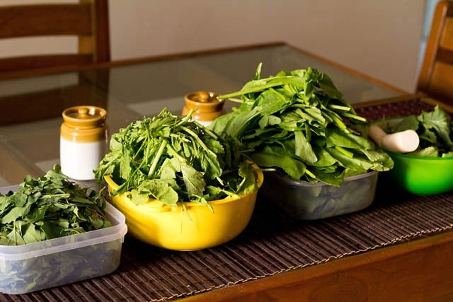 prepped greens for sarson ka saag in bowls on a table.