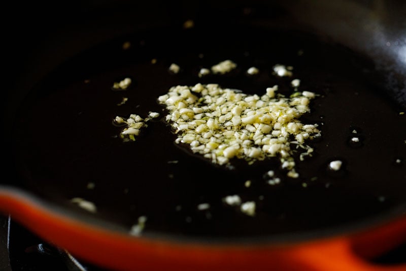 finely chopped garlic added to olive oil in a black skillet