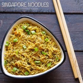 singapore noodles served in a white bowl with chopsticks on the side and text layover.