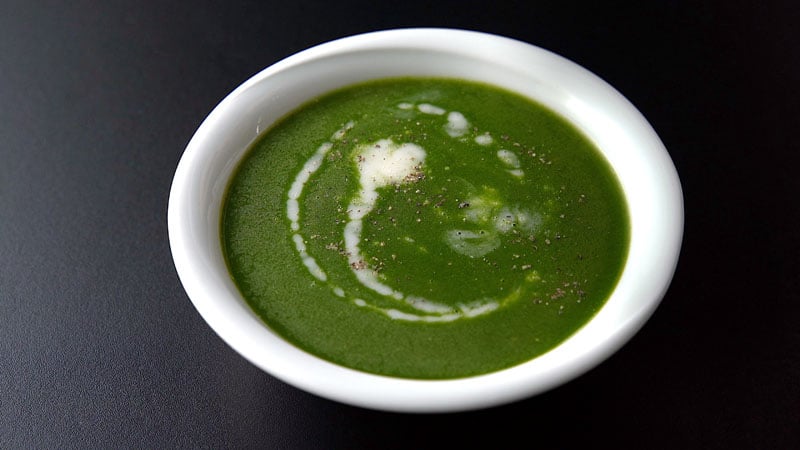 spinach soup in a bowl with a drizzle of coconut cream on top