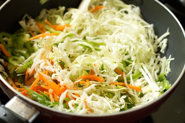 shredded veggies added to pan with oil and green onions