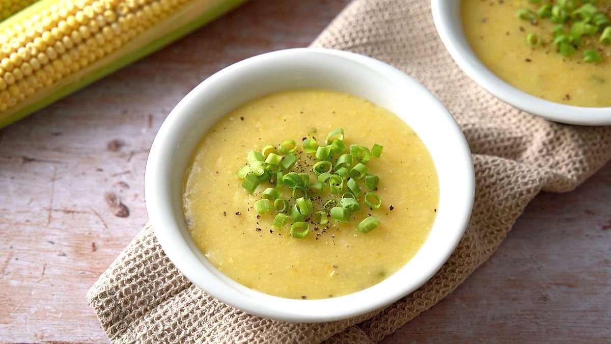 sweet corn soup in white bowl garnished with spring onion greens