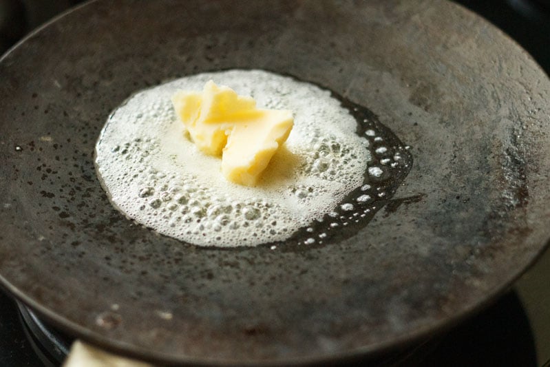butter getting melted on a black tawa. 
