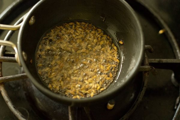 cumin seeds crackling and sizzling in black tadka pan