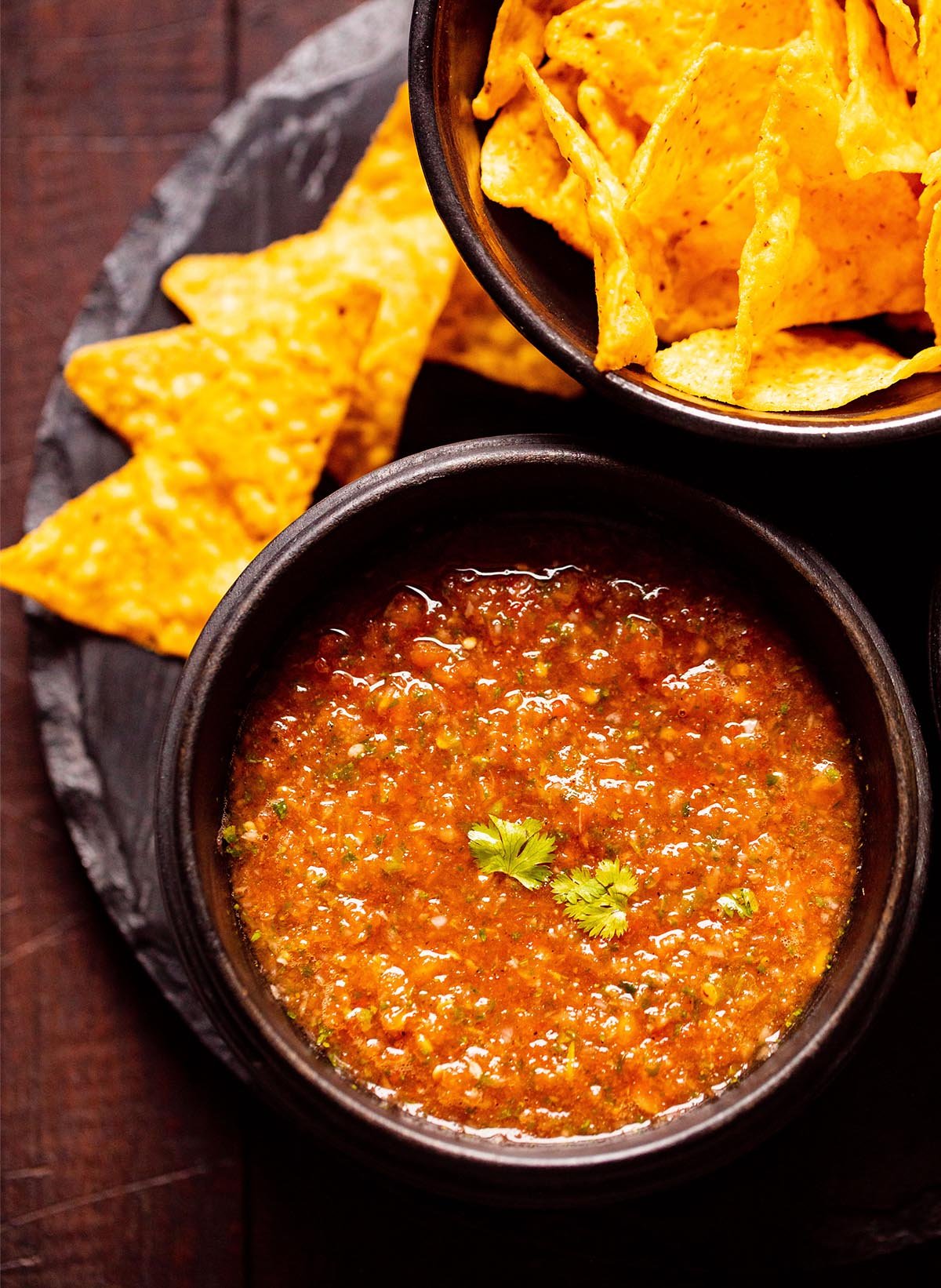 homemade tomato salsa in a black wooden bowl with tortilla chips