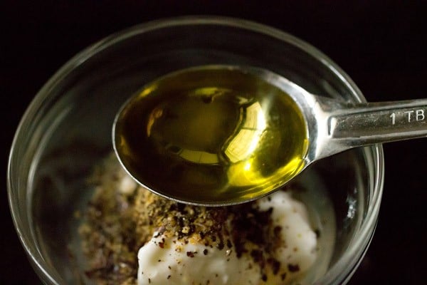 olive oil being added with a measuring spoon